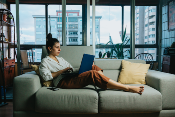 woman holding laptop while sitting on sofa