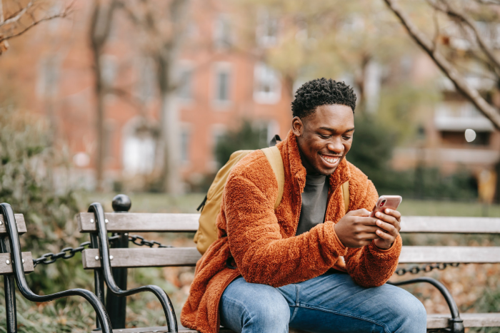 Man texting at a park in relation to real estate text message marketing