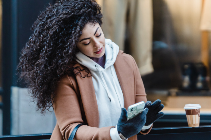Woman using her phone outside with gloves on
